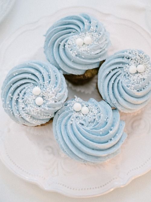 three frosted cupcakes sitting on top of a white plate with blue icing