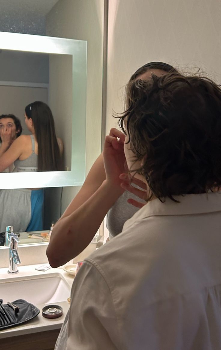 a woman standing in front of a bathroom mirror