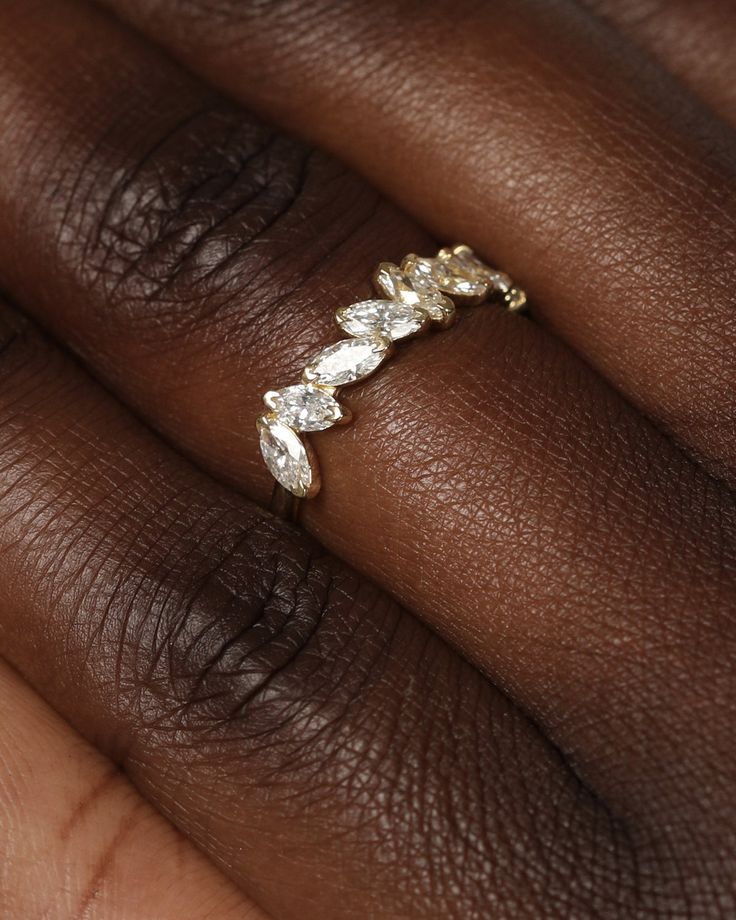 a woman's hand wearing a gold ring with three pear shaped diamonds on it