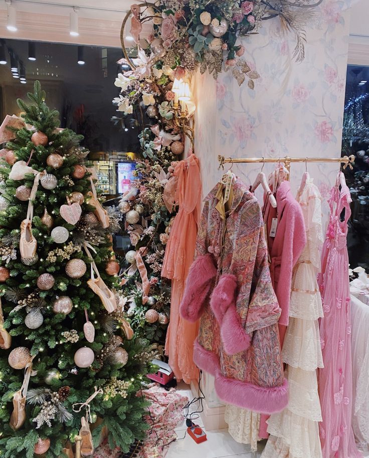 there is a christmas tree in the store with clothes hanging from it's racks