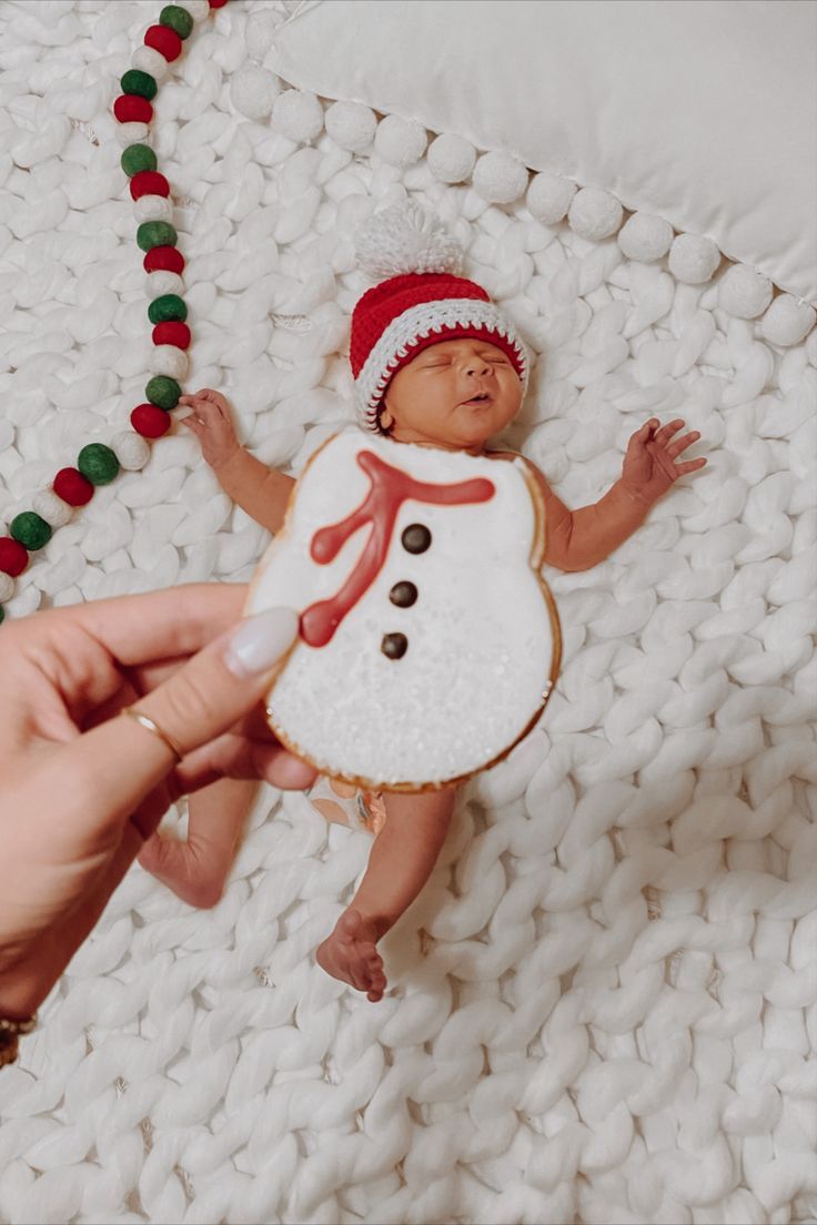 a person holding a baby wearing a snowman cookie on top of a white blanket