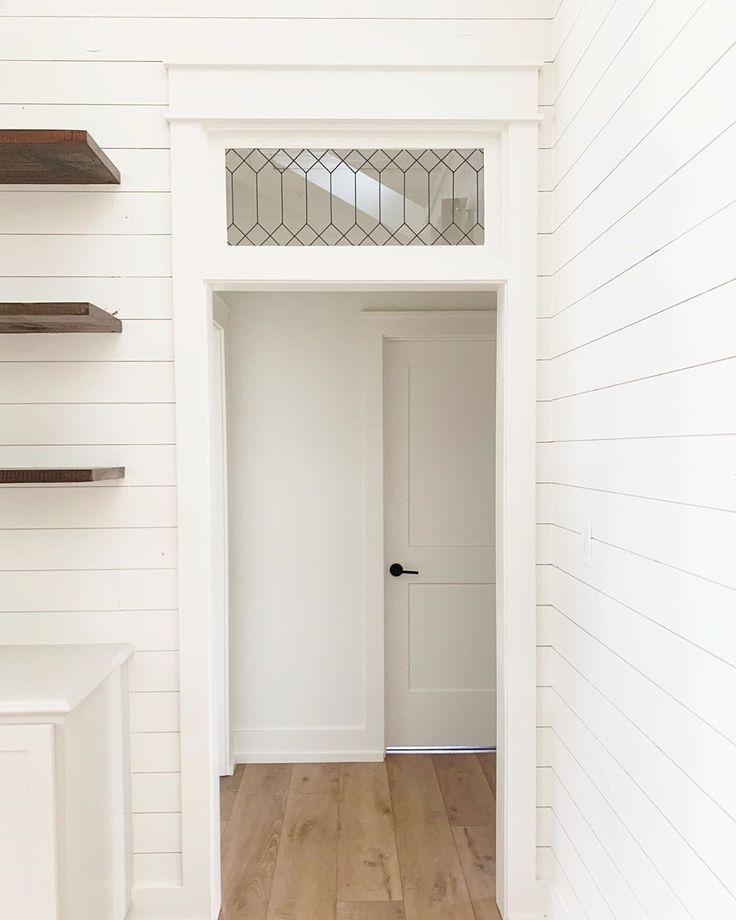 an empty room with white walls and wood floors is seen from the doorway to the hallway