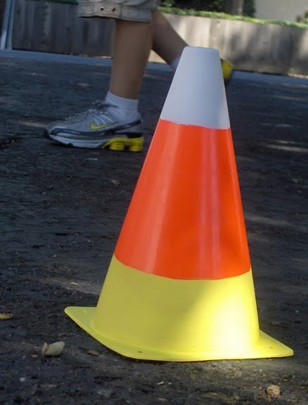 an orange and white cone sitting on the ground next to a person's feet