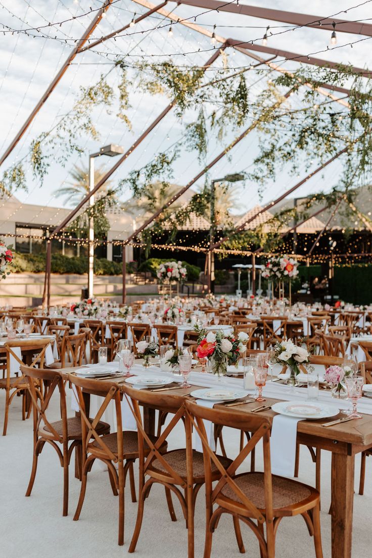 tables and chairs are set up for an outdoor wedding reception under a tented area