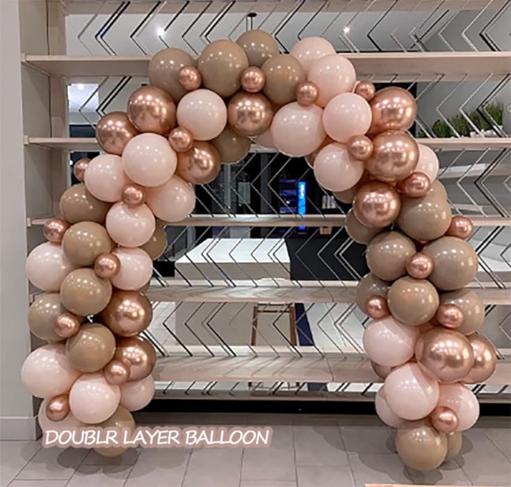 a large balloon arch with pink, gold and white balloons in the shape of a wreath