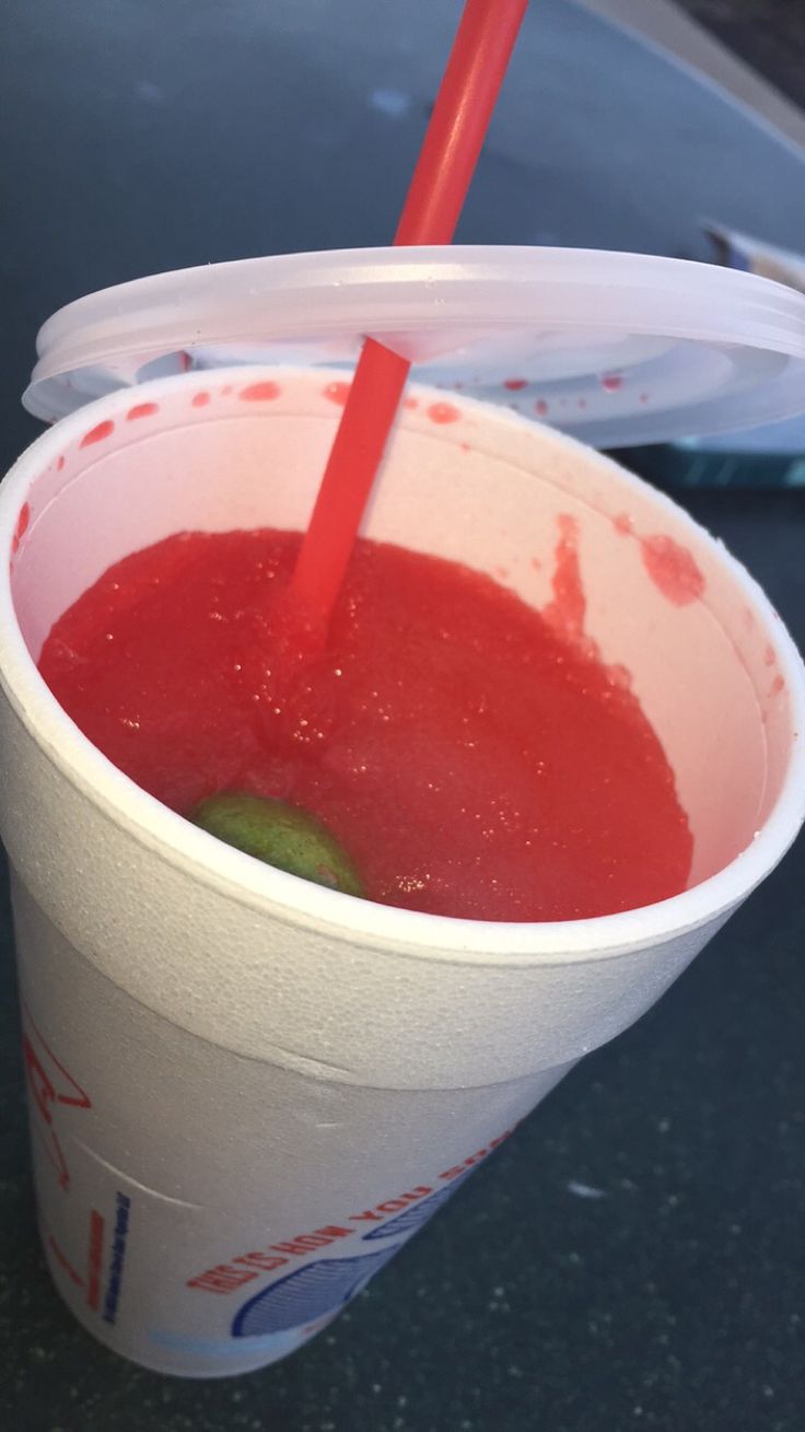 a plastic cup filled with red liquid and a straw sticking out of the top, sitting on a table