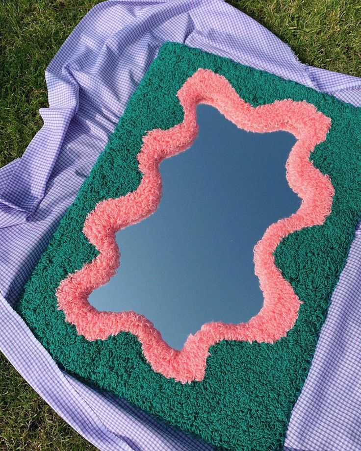 a green and pink cake sitting on top of grass