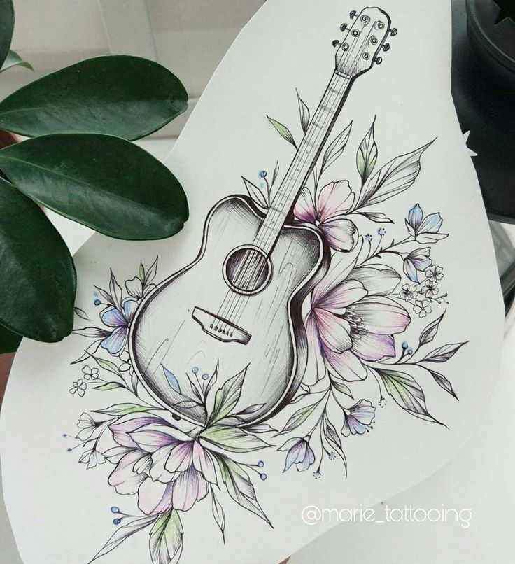 a guitar with flowers and leaves on the back of it, next to a potted plant