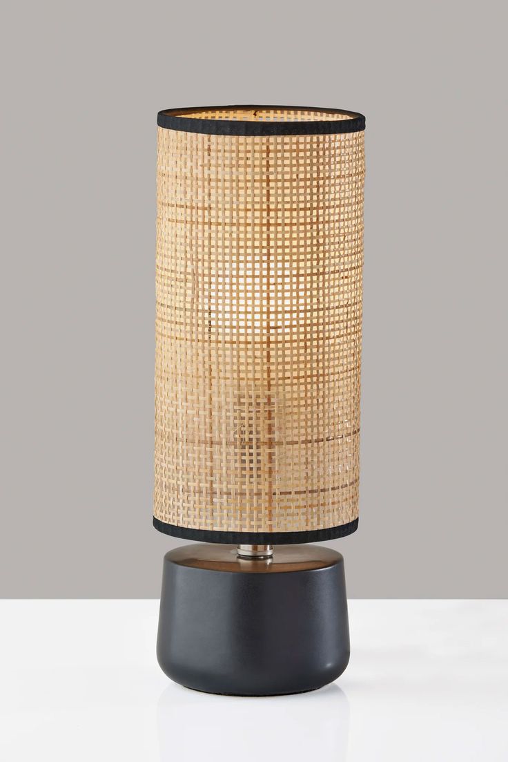 a table lamp with a black base and brown shade on the top, sitting on a white surface