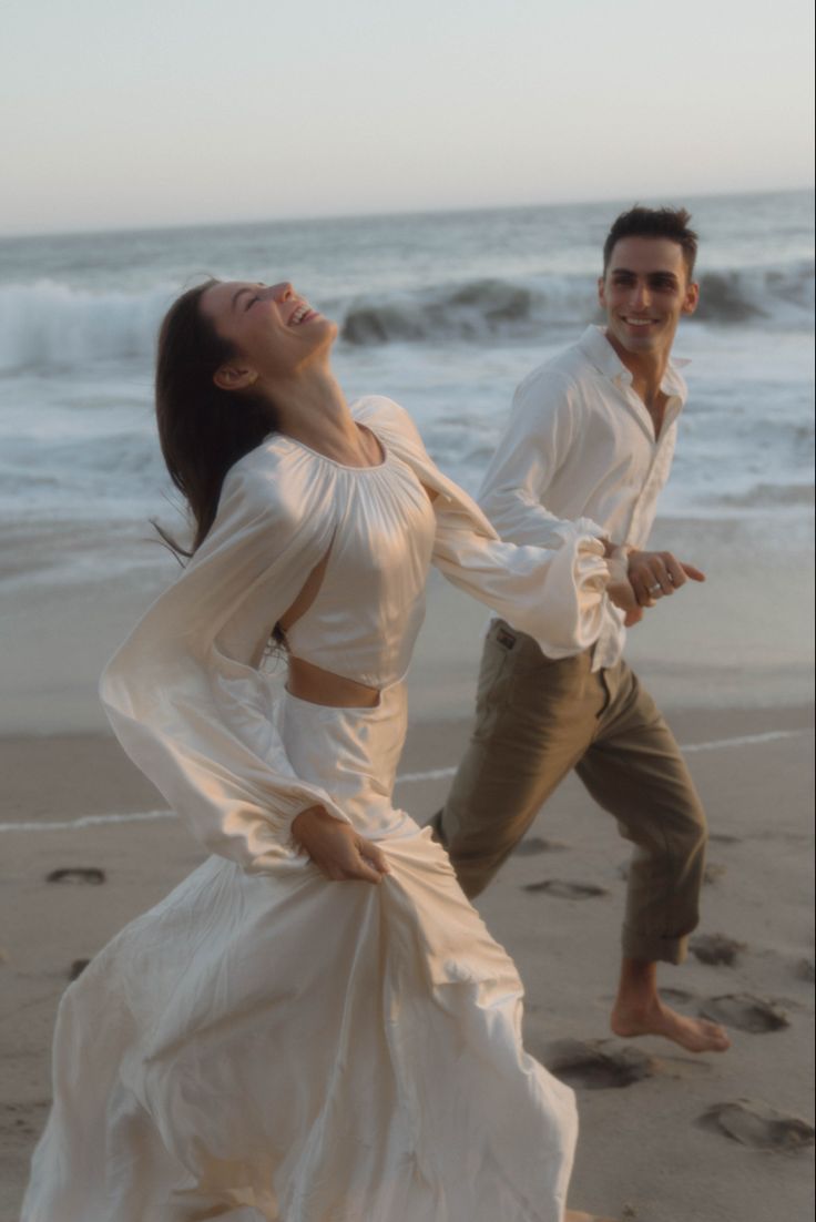 a man and woman dancing on the beach