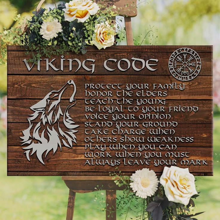 a wooden sign with the words viking code written on it and flowers in front of it