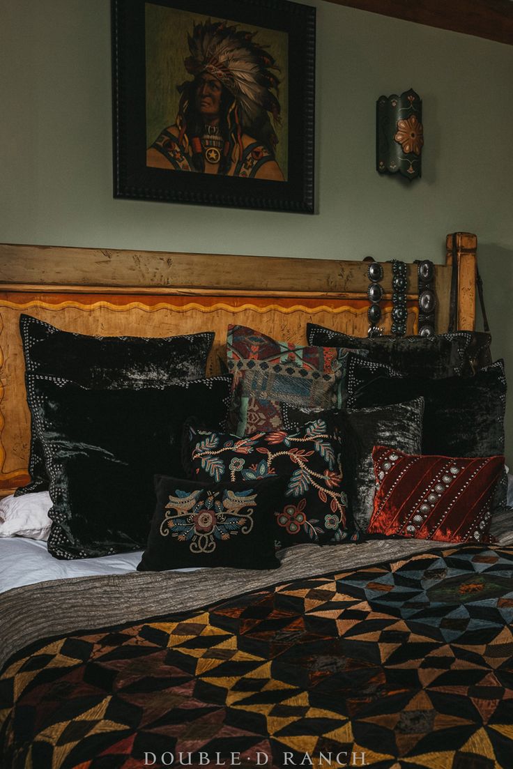 a bed with pillows and blankets on top of it in a bedroom next to a painting