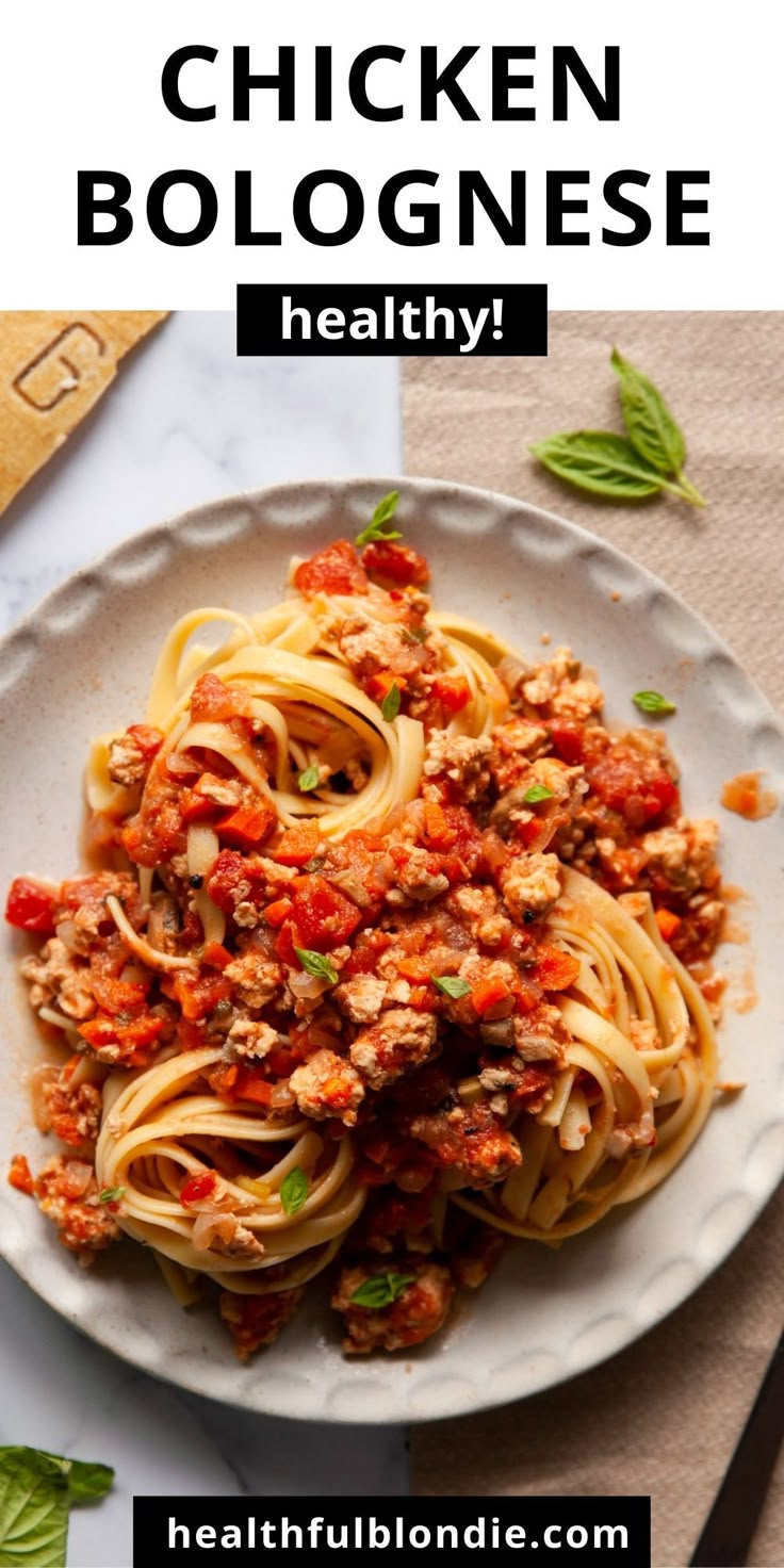 a white plate topped with pasta covered in chicken bolognzoe and garnished with basil leaves