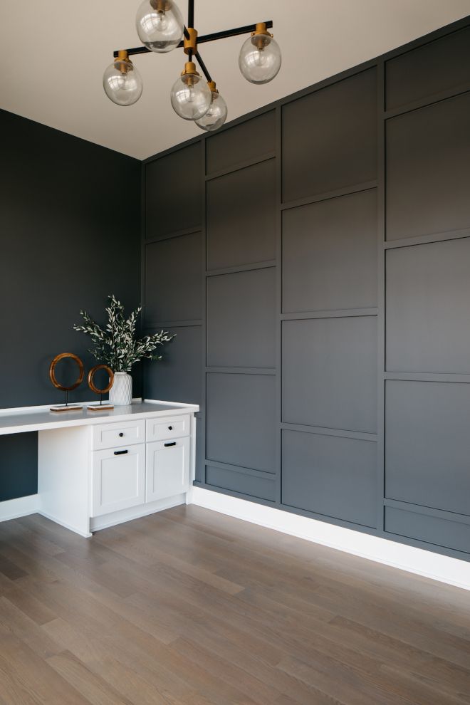 an empty room with wood flooring and gray wallpaper on the walls, along with a white table topped with a vase filled with flowers