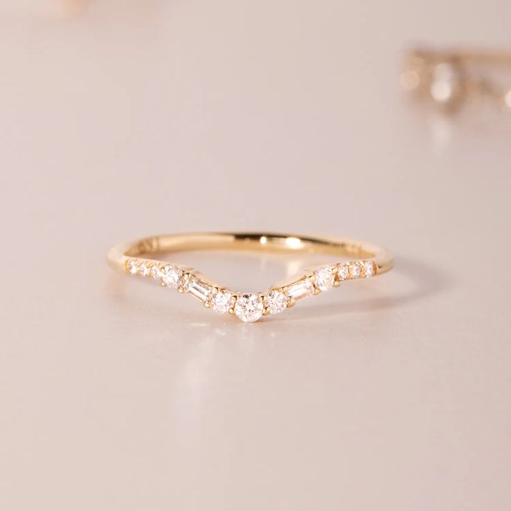 a gold ring with three small diamonds on the top and one smaller diamond in the middle