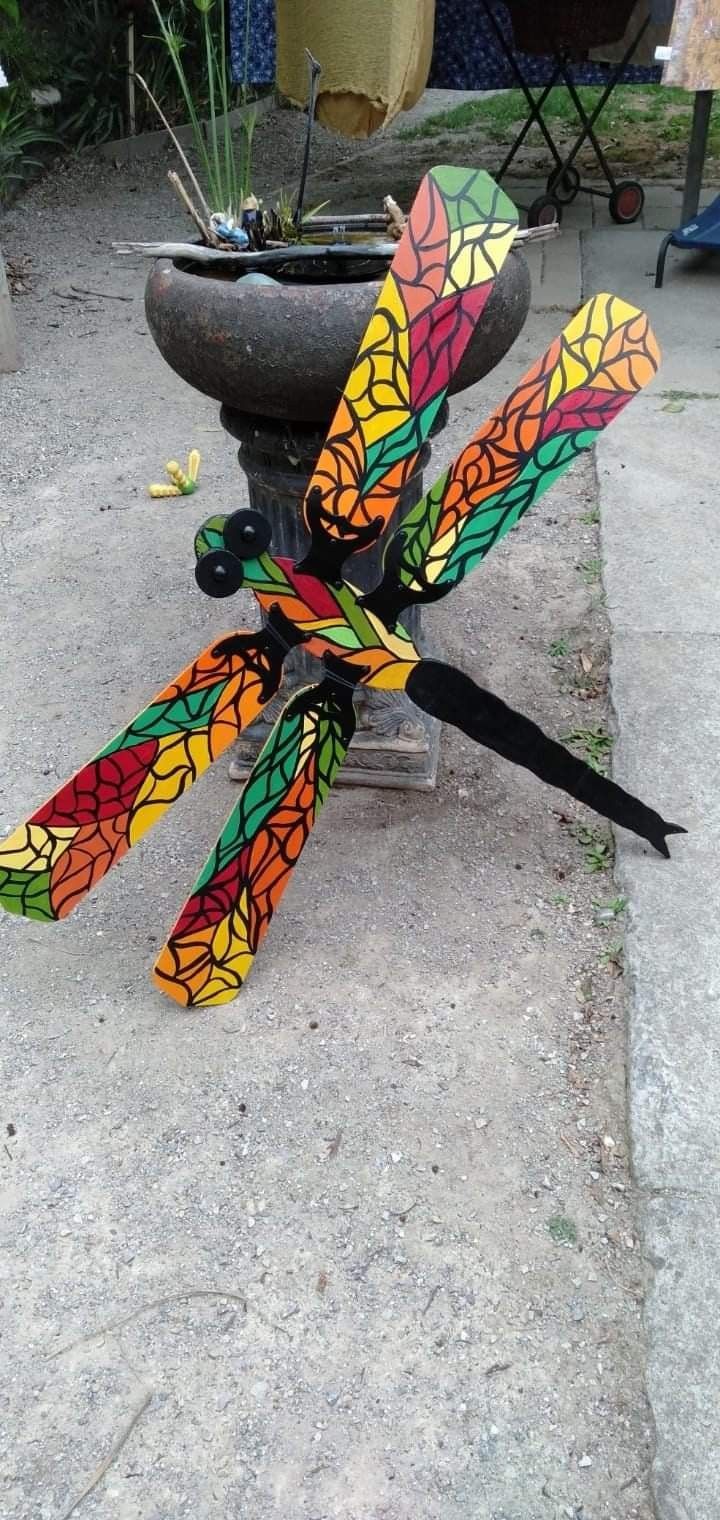 colorful dragonflys are tied to a stone pedestal in front of a potted plant