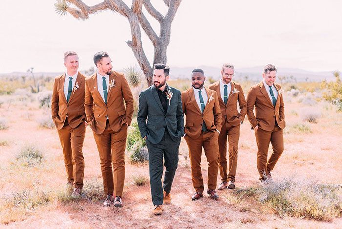 a group of men in brown suits and ties standing next to each other near a tree