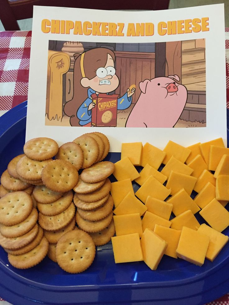 crackers and cheese on a blue plate next to a card with an image of a cartoon character