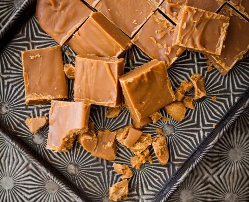 peanut butter fudge bars on a plate with pieces cut out and scattered around them