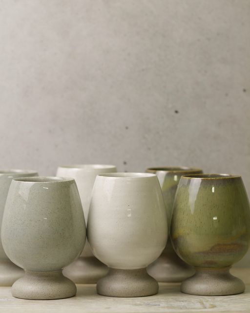 five white and green vases lined up on a table