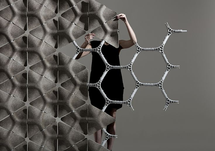 a woman standing in front of a wall made out of hexagonal objects