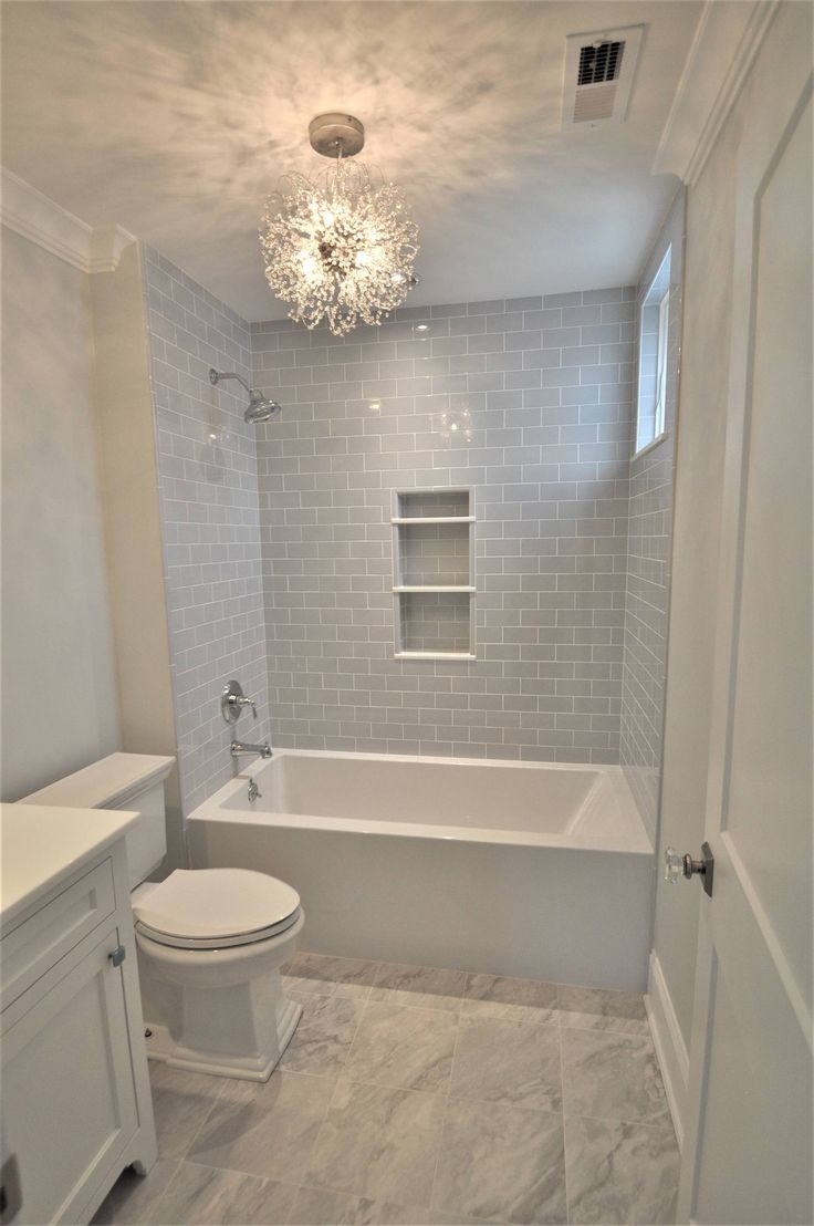 a white toilet sitting next to a bath tub under a chandelier in a bathroom