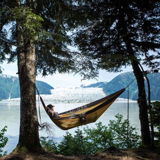 a man is laying in a hammock by the water