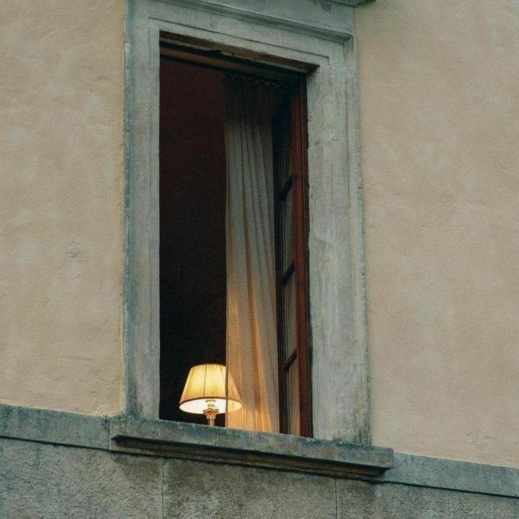 an open window with curtains and a lamp in it