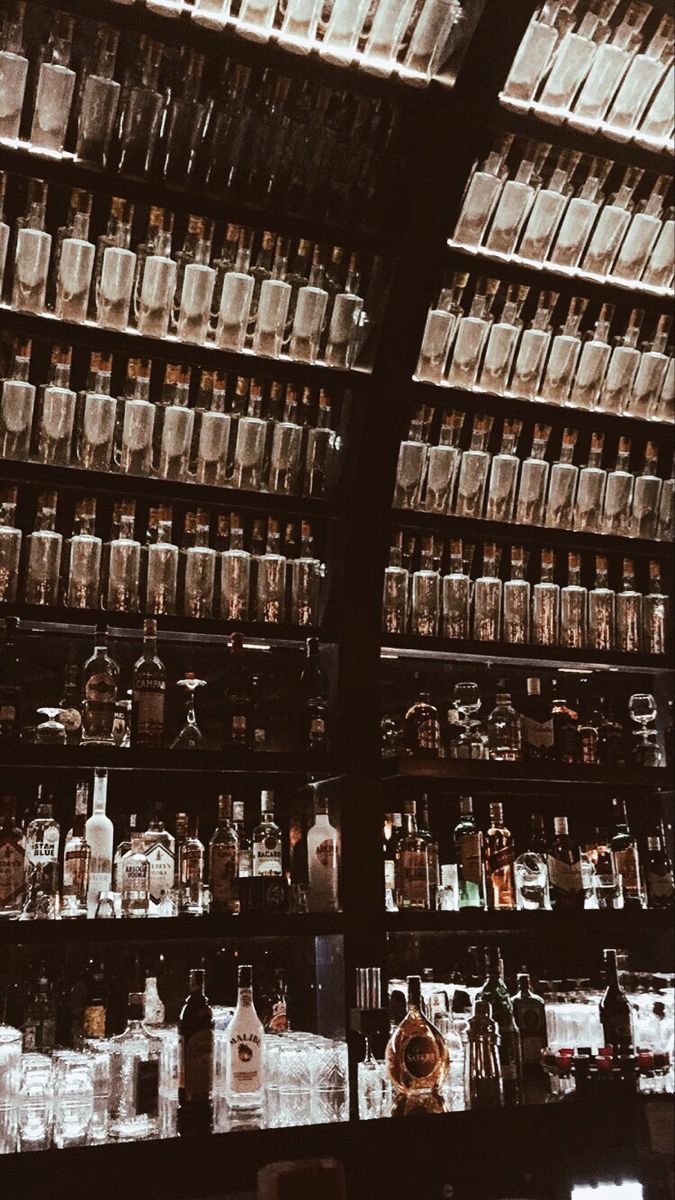 shelves filled with bottles and glasses on top of each other in a room full of glass containers