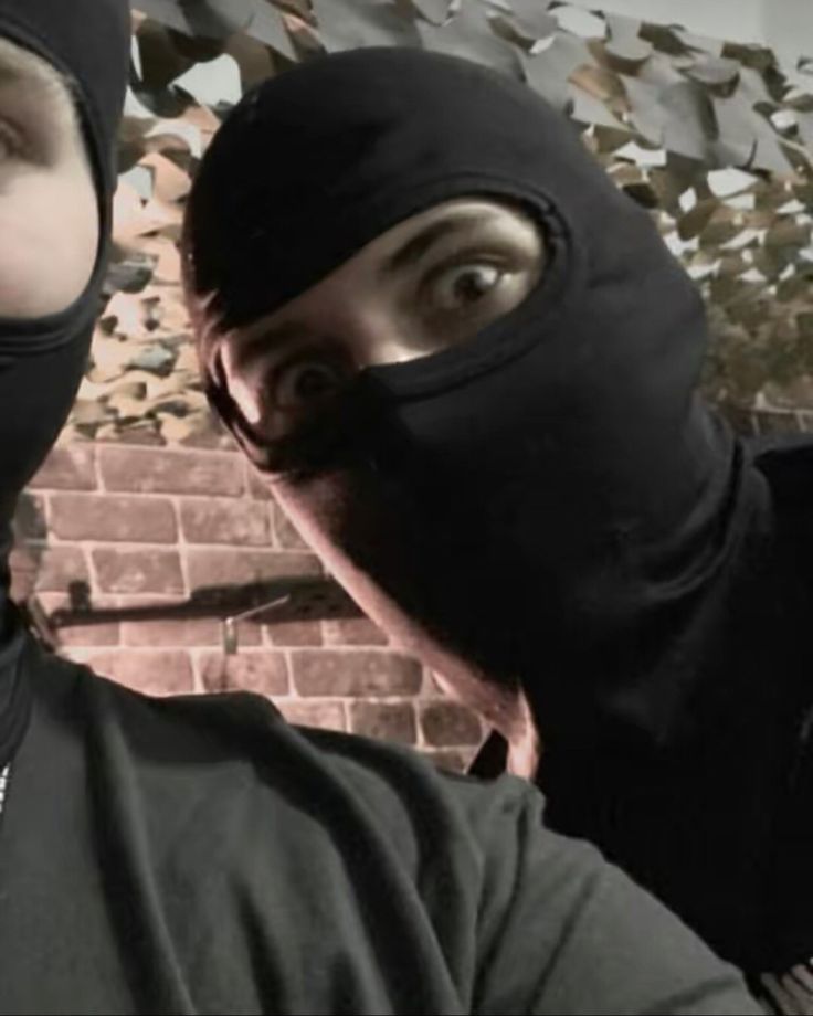 two people wearing black masks and one is looking at the camera