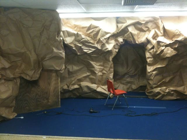 a red chair sitting on top of a blue floor next to a rock covered wall