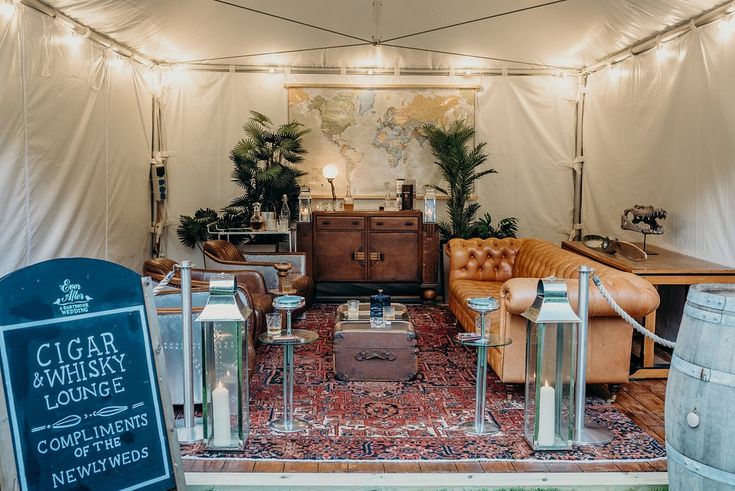 a living area with couches, chairs and a sign in front of the tent