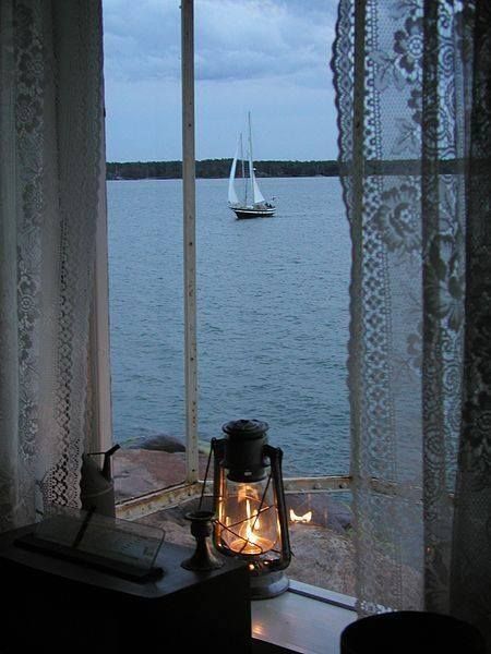 there is a lantern sitting on the window sill in front of the water and boats