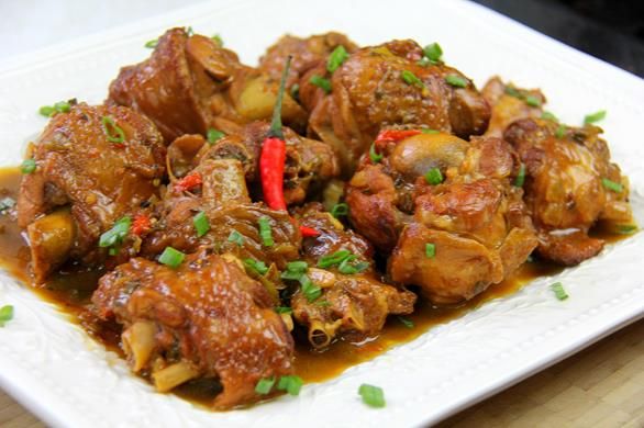 a white plate topped with meat covered in sauce and garnished with green onions