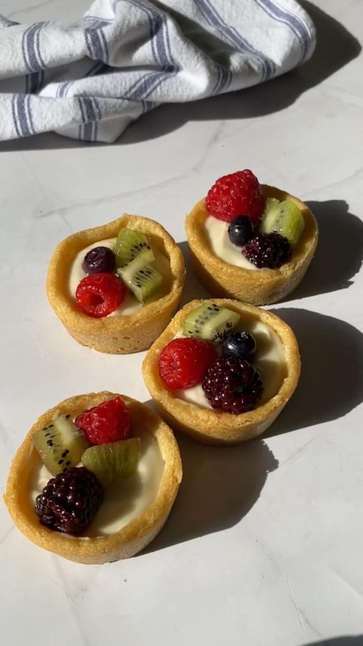 four mini fruit tarts sitting on top of a table