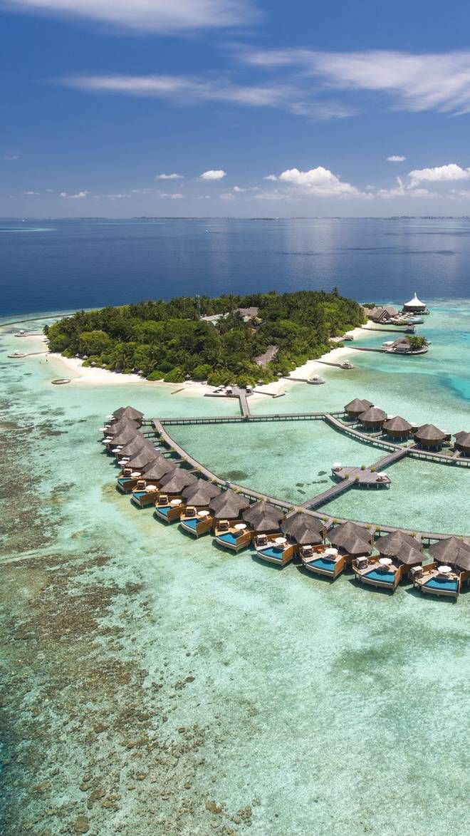 an aerial view of a resort in the middle of the ocean with over water beds and thatched huts