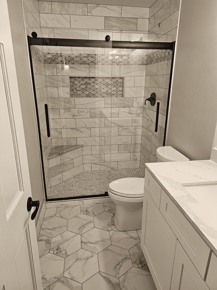 a bathroom with a toilet, sink and shower stall in black and white photo taken from the doorway