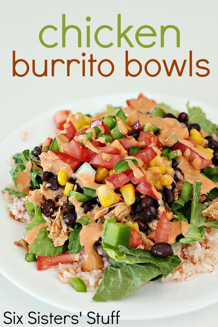 chicken burrito bowls on a white plate with rice and black beans, garnished with avocado