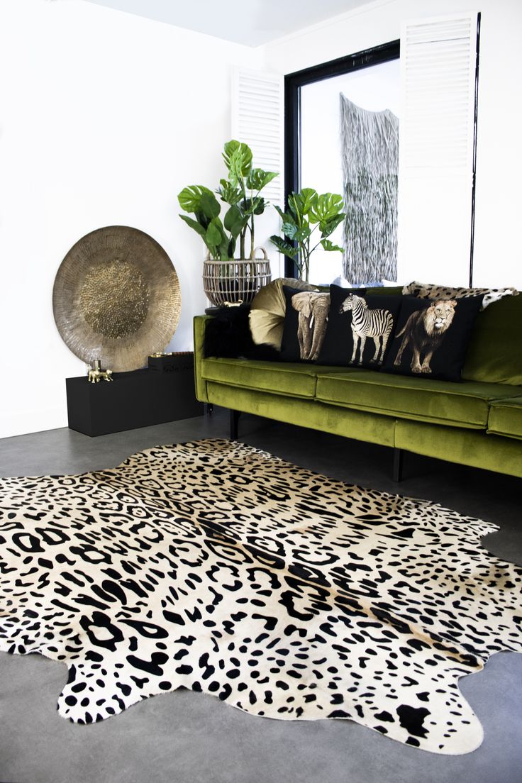 a living room with a green couch and animal print rugs on the floor next to a large mirror