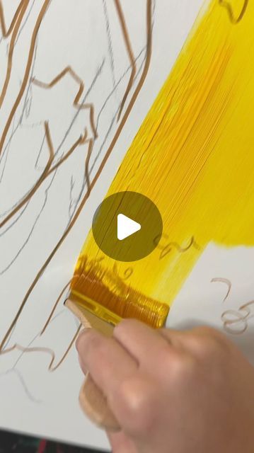 someone is painting with yellow paint on a white canvas and holding a brush in their hand