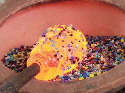 a yellow bottle with sprinkles sitting in a pot filled with dirt and gravel