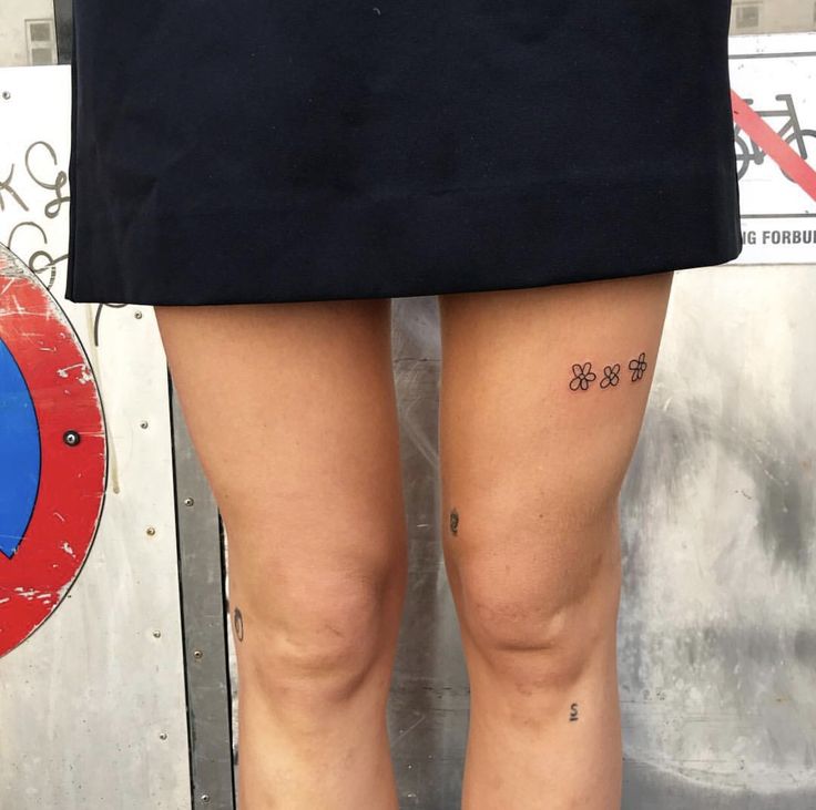 a woman with tattoos on her legs standing next to a wall