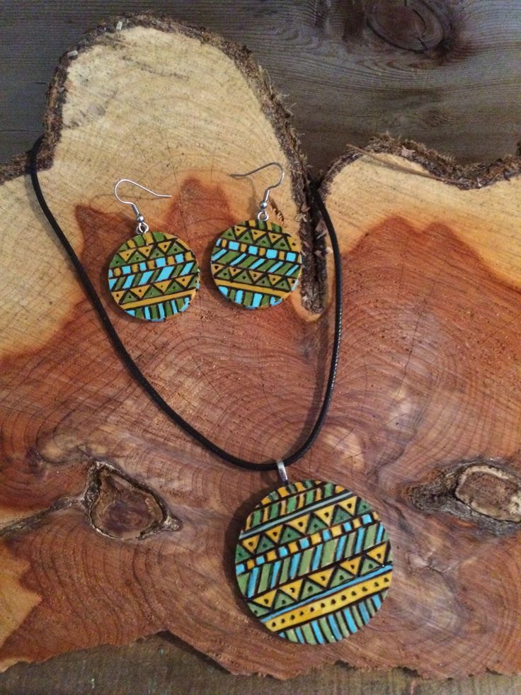 a necklace and earring set sitting on top of a piece of tree trunk next to a slice of wood