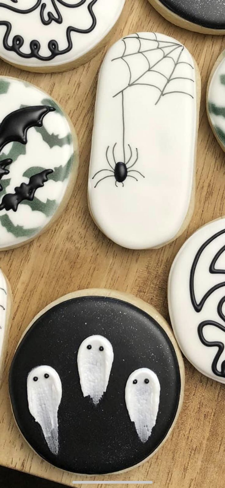 decorated cookies with white icing and black frosting on top of a wooden table