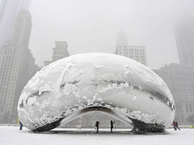 two people standing in front of a large white object with snow on it's surface