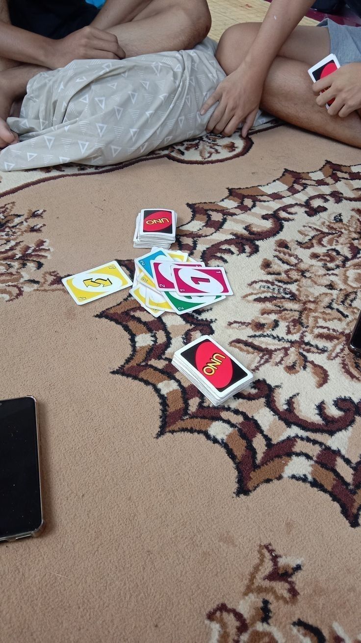 several people sitting on the floor playing with their cell phones and cards in front of them