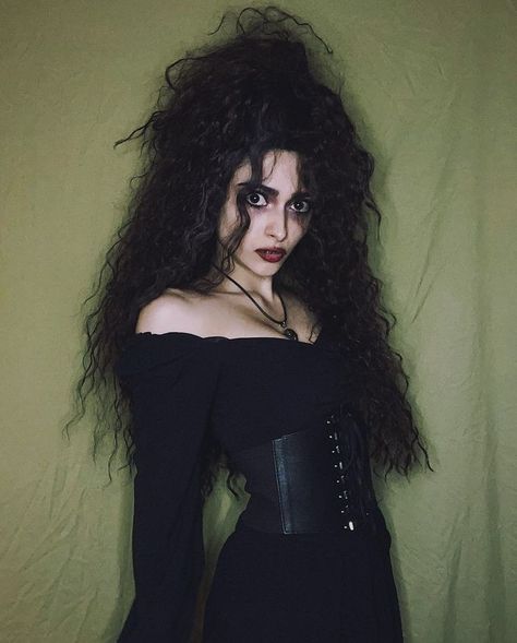 a woman with long hair wearing a black corset and choker, standing in front of a green wall