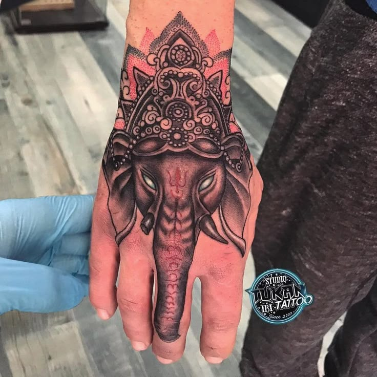 an elephant's head is on the hand of a man with intricate patterns around it