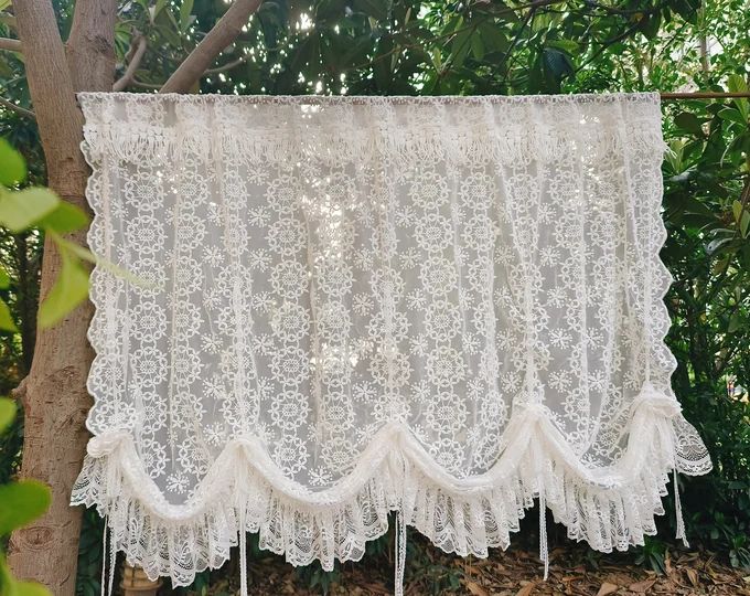 a white lace curtain hanging from a tree