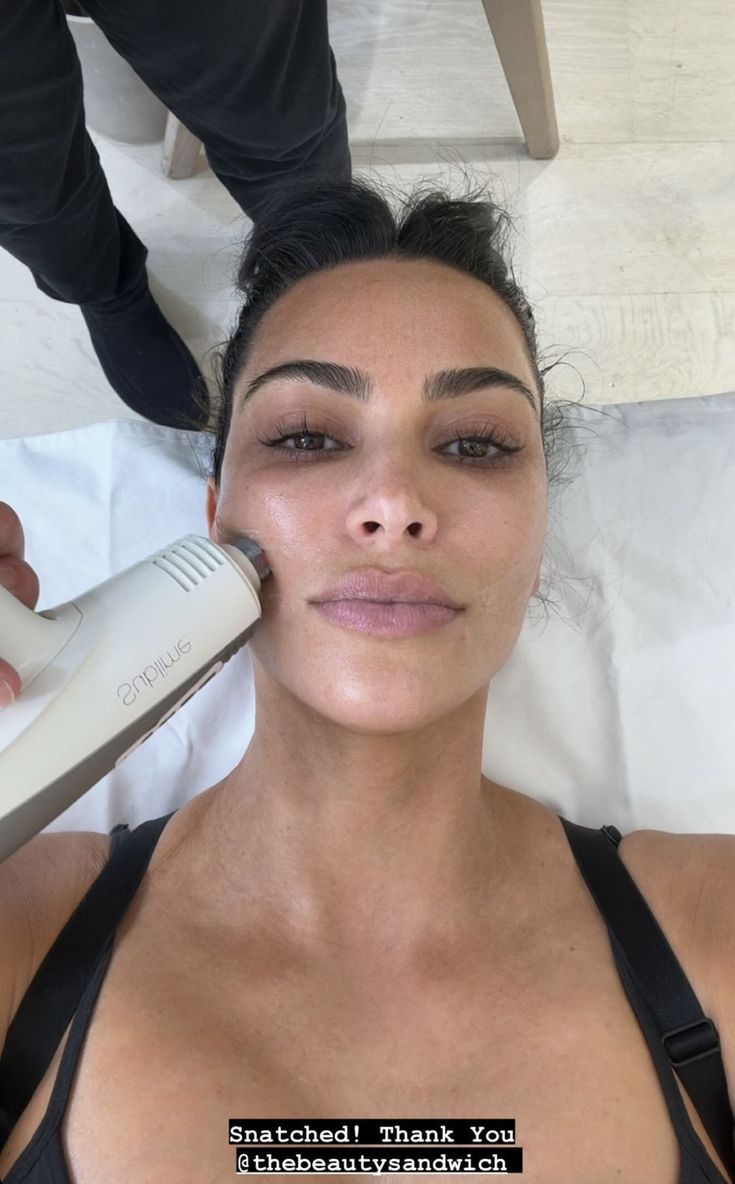 a woman getting her eyebrows brushed by an electric hair dryer